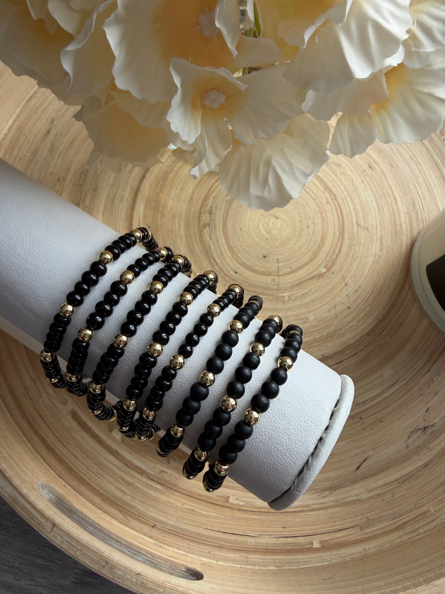 Gold-filled beaded bracelet with black beads stacked with minimalist gold bracelets