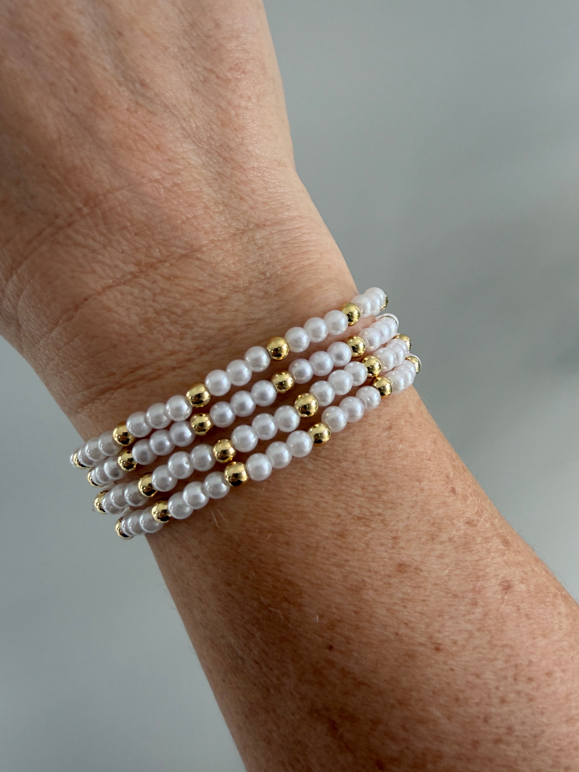 Gold-filled beaded bracelet with pearls stacked with minimalist gold jewelry
