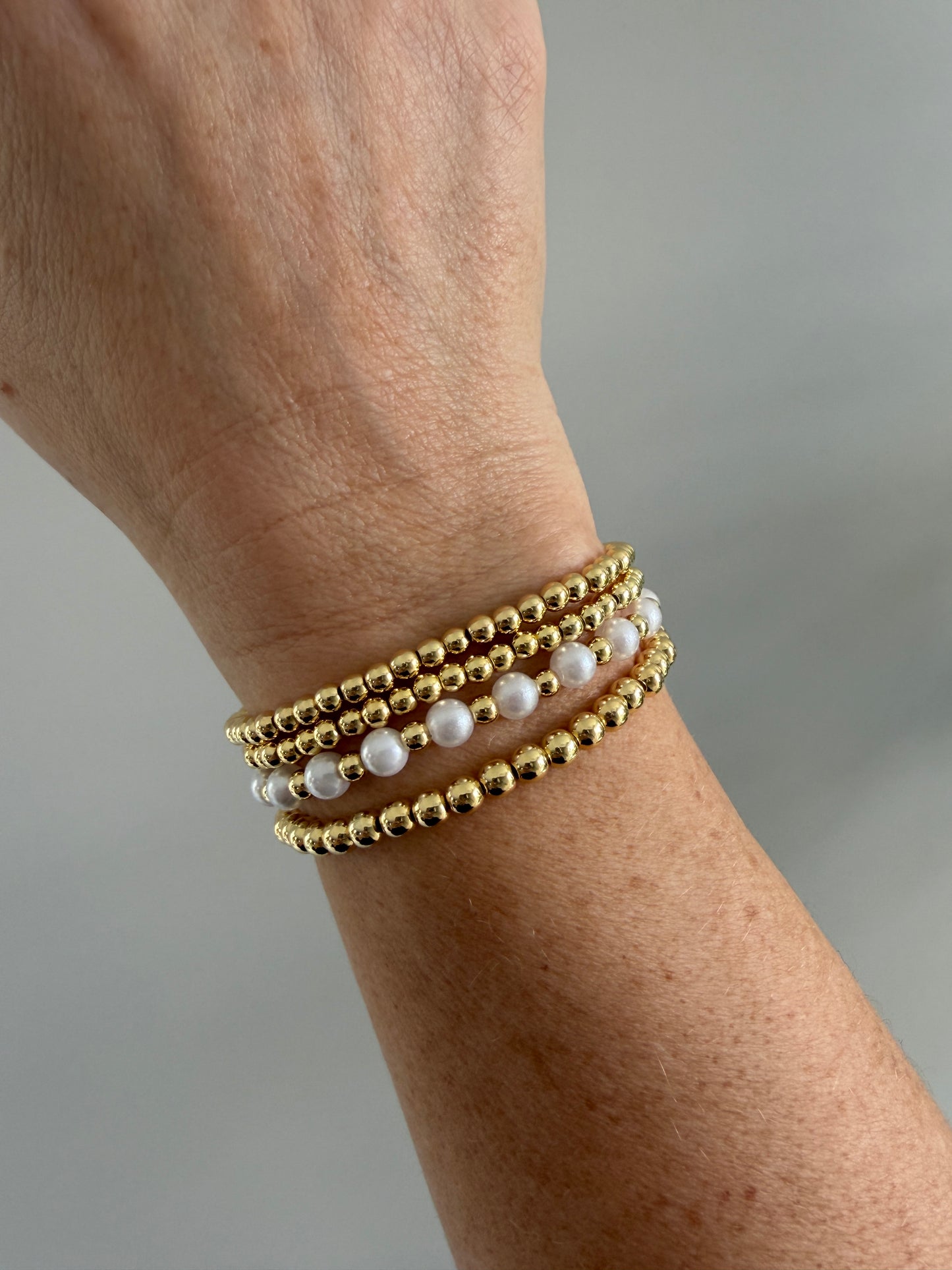 Gold-filled beaded bracelet with pearls stacked with minimalist gold jewelry