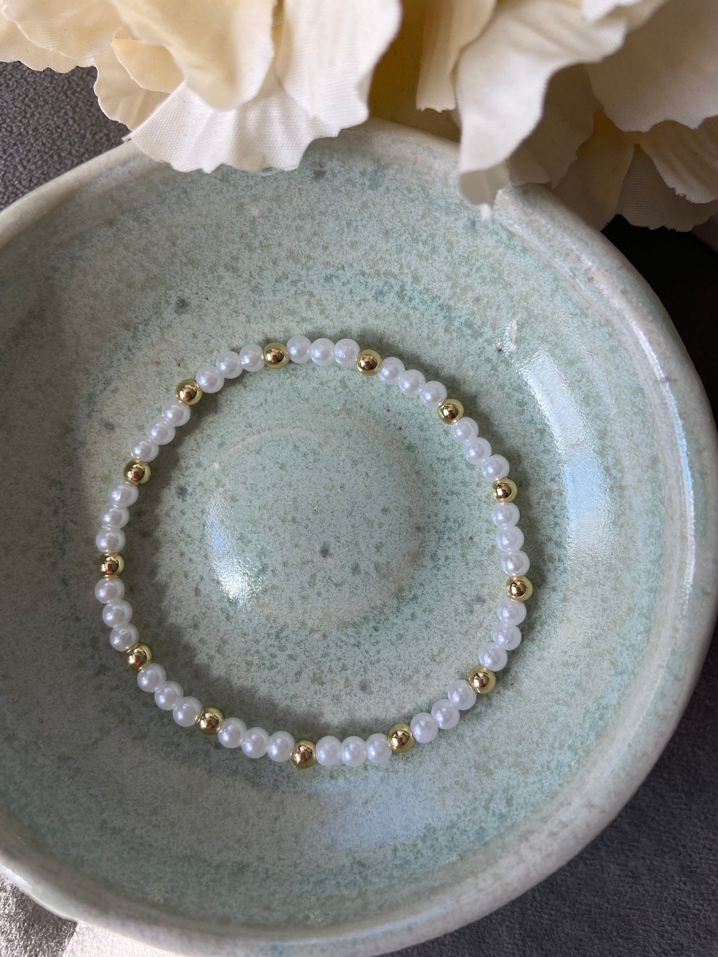 Pearl bracelet with gold accents on a ceramic dish