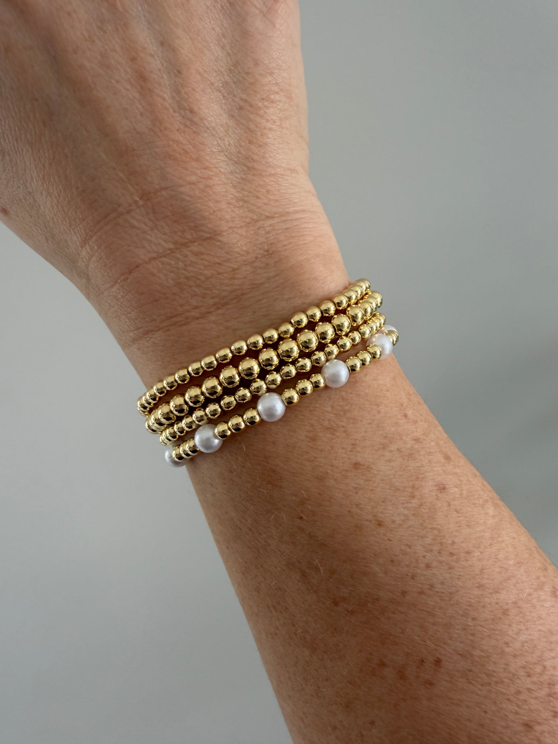Gold-filled beaded bracelet with pearls stacked with minimalist gold jewelry