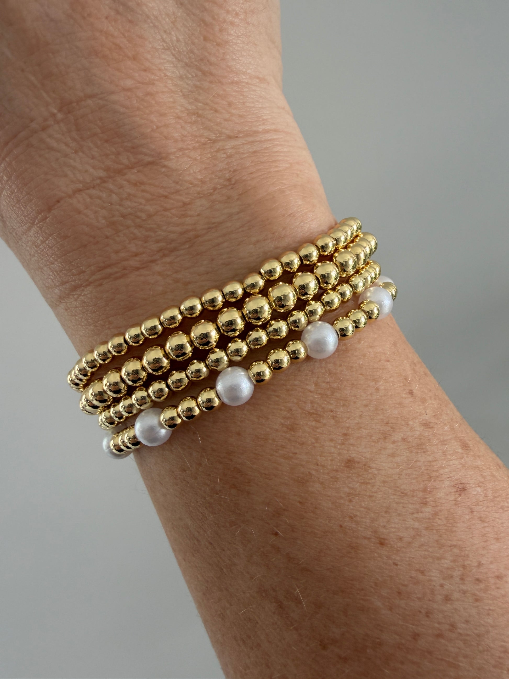 Gold-filled beaded bracelet with pearls stacked with minimalist gold jewelry