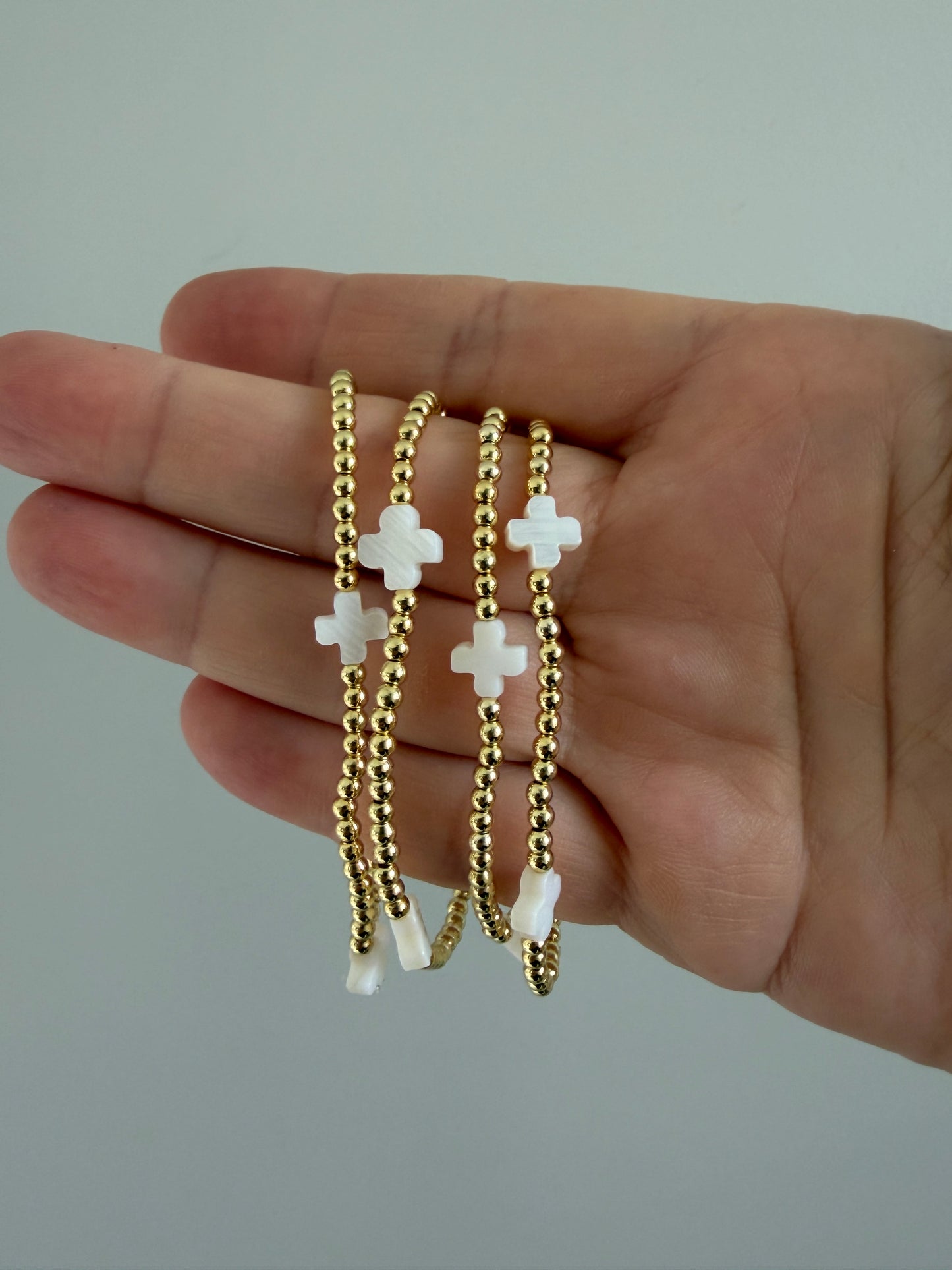 18k gold-filled beaded bracelet with white crosses on neutral background