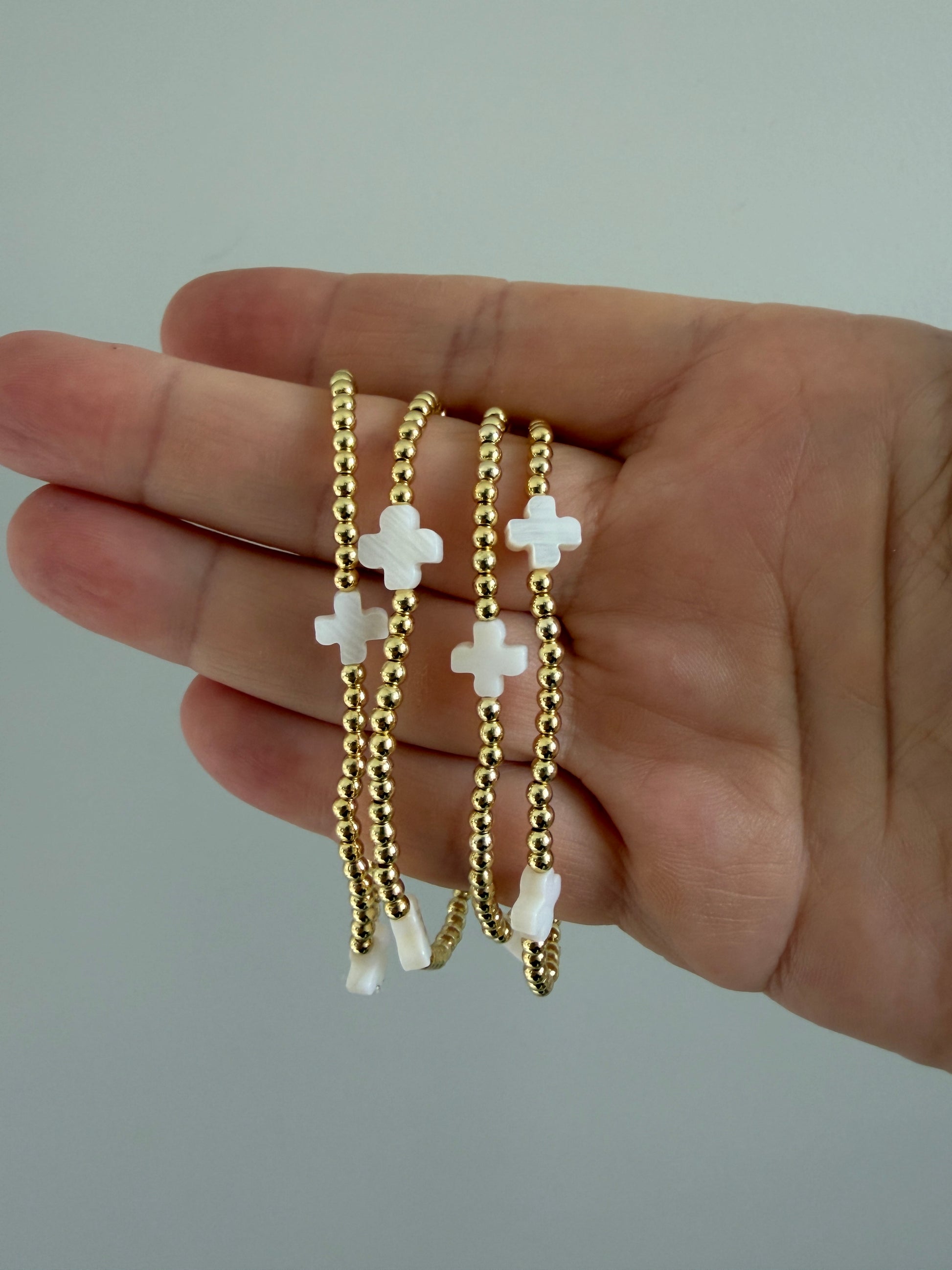 18k gold-filled beaded bracelet with white crosses on neutral background