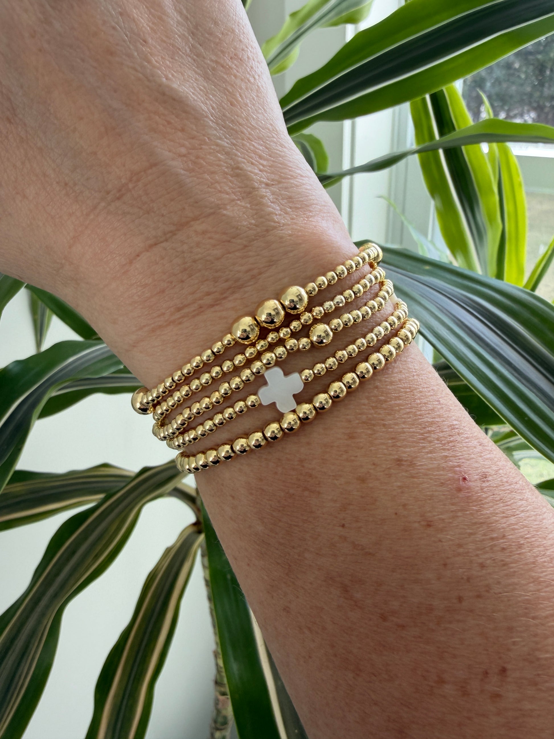 Stacked 18k gold-filled bracelets with white cross design, handmade beaded jewelry
