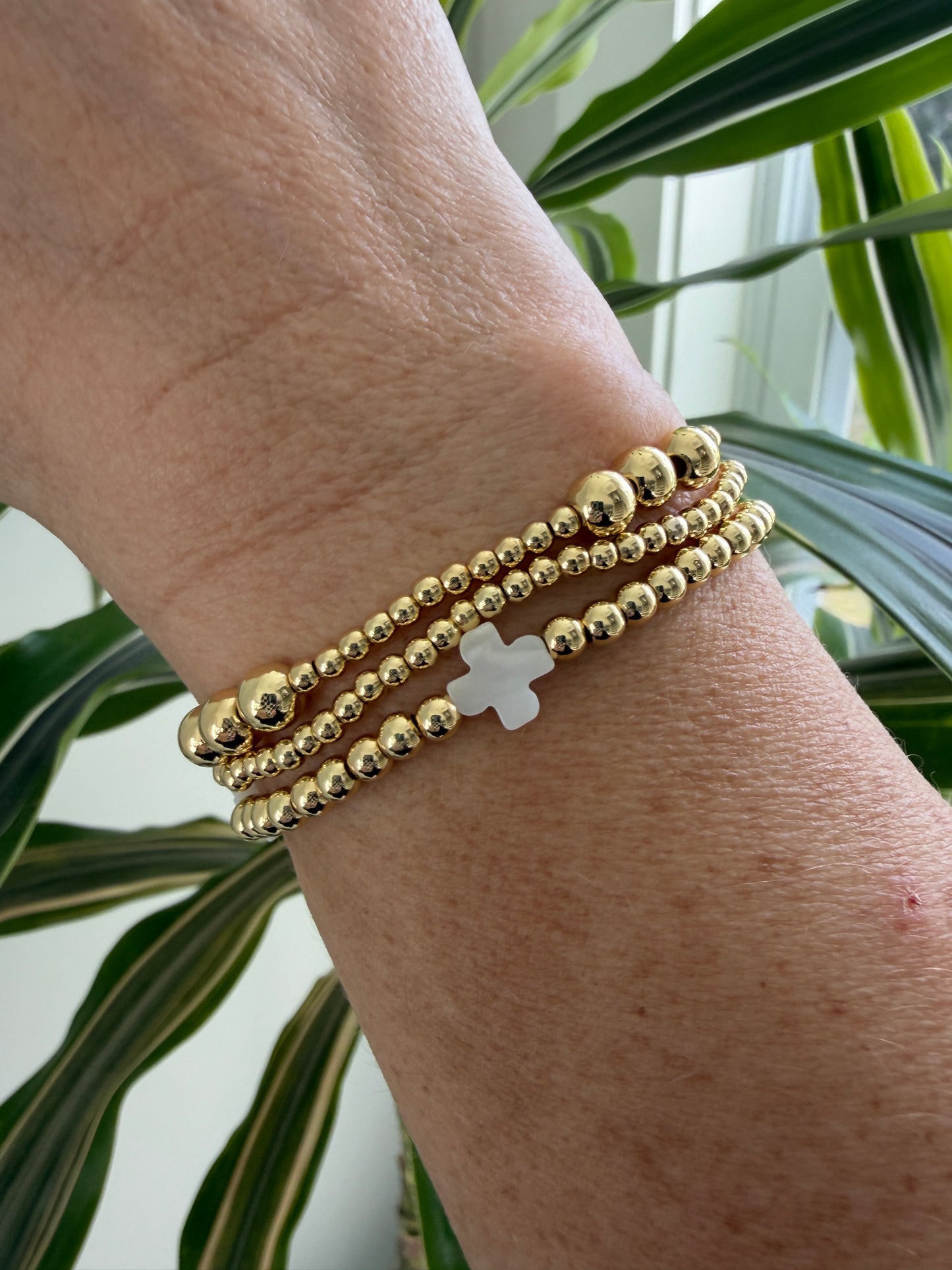 Stacked 18k gold-filled bracelets with white cross design, handmade beaded jewelry