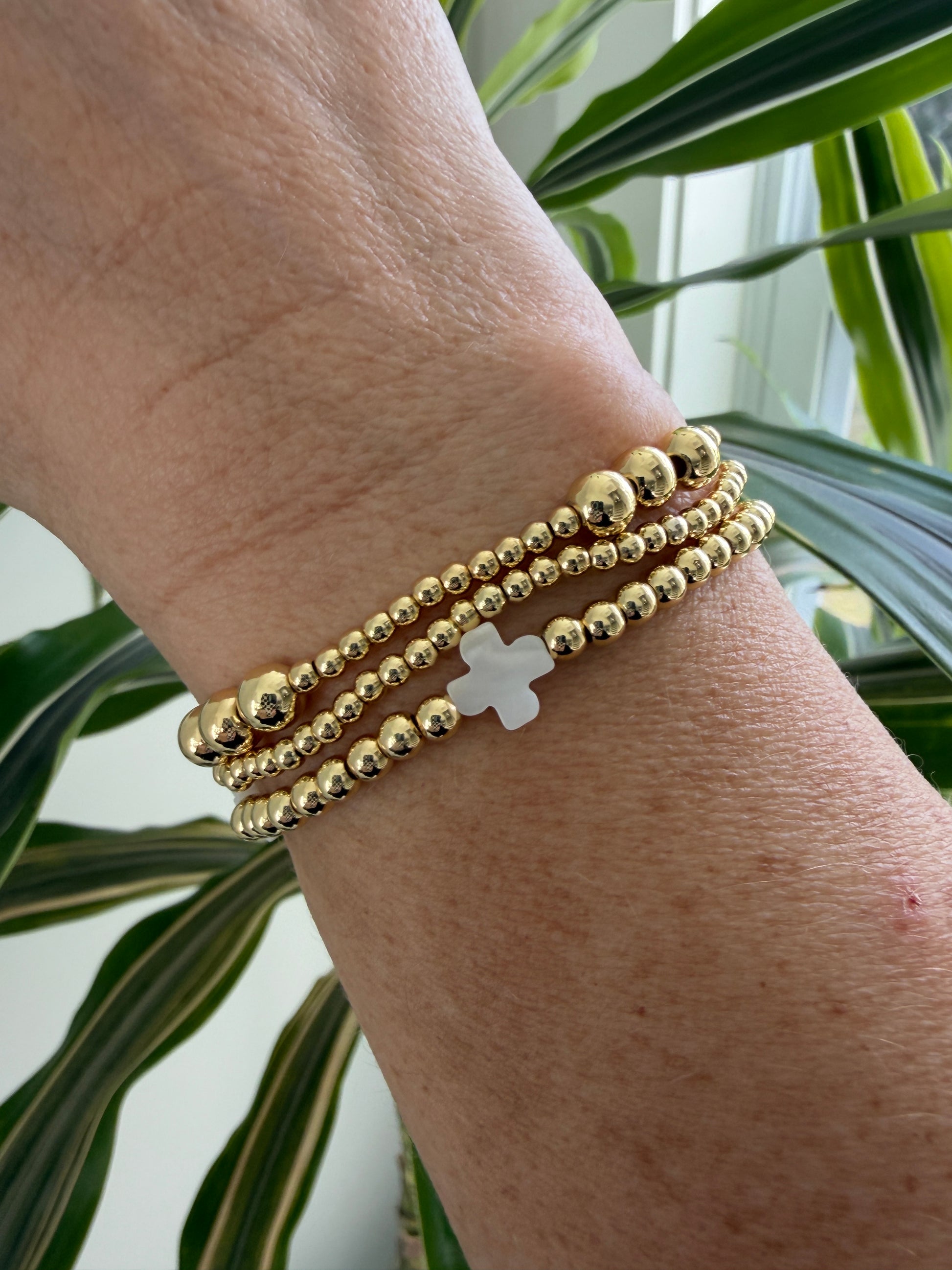 Stacked 18k gold-filled bracelets with white cross design, handmade beaded jewelry