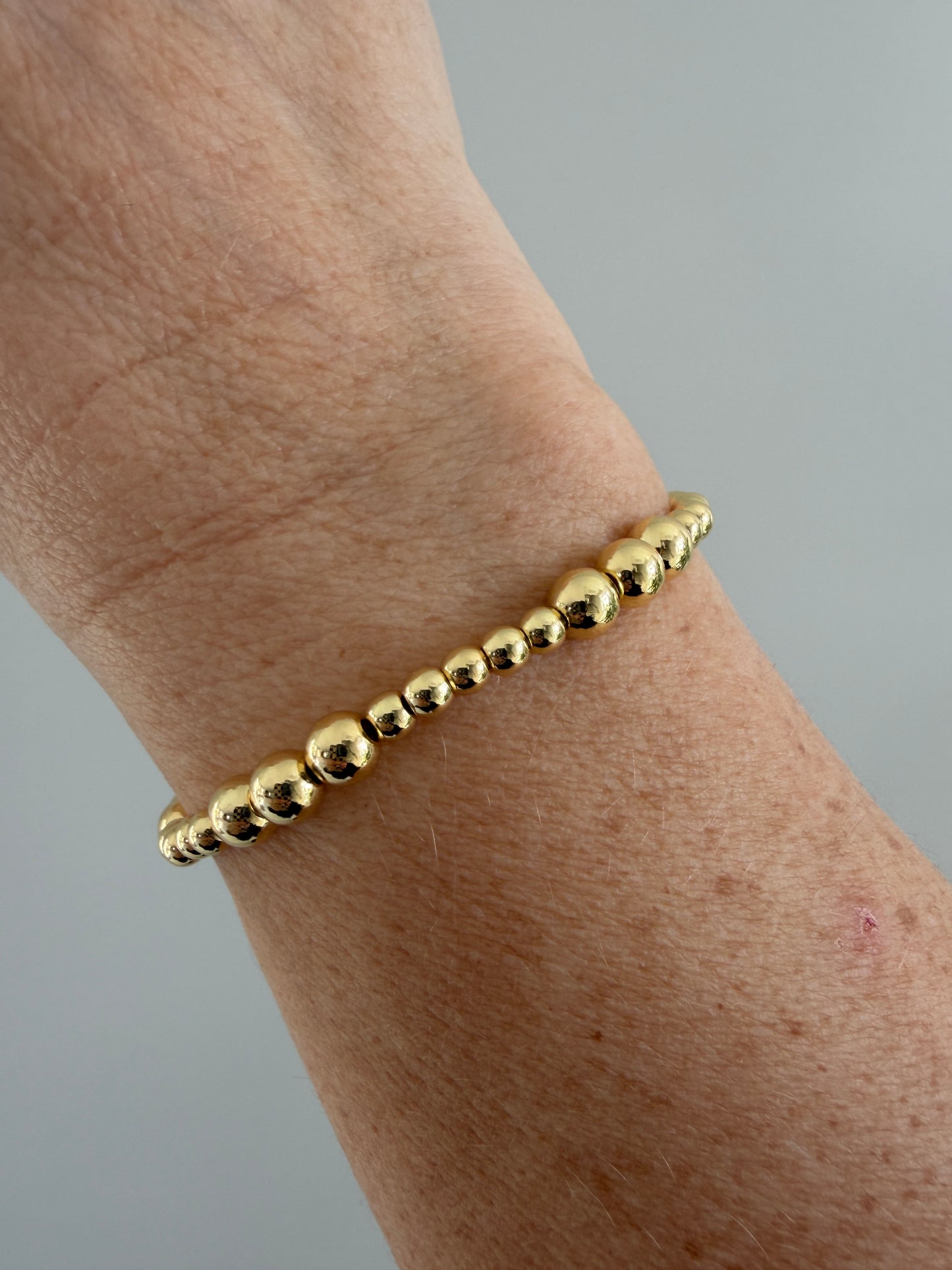 Hand wearing a delicate 18K gold-filled bracelet, minimalist everyday jewelry
